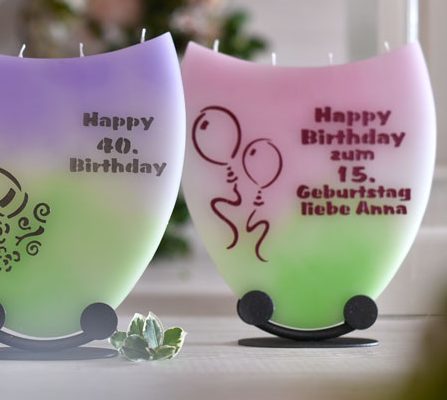 Zwei bunte Kerzen, individuell gestaltet für den 40. und 15. Geburtstag, stehend auf einem Tisch.